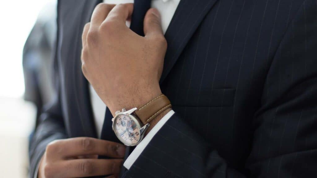 Closeup photo of businessman with expensive watch adjusting his tie