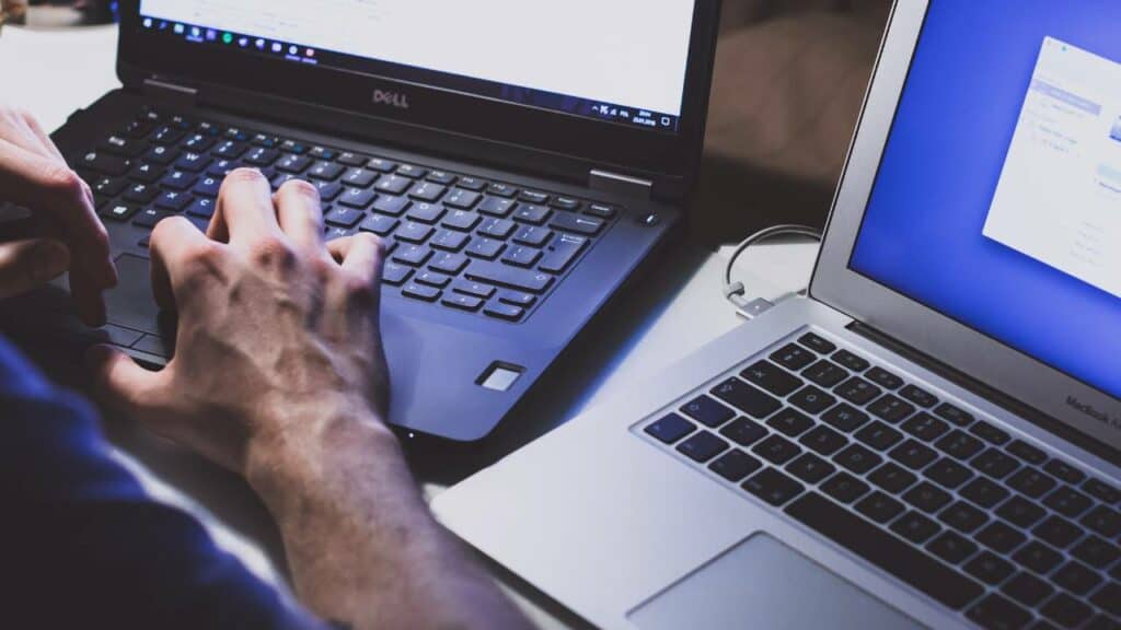 A photo of man's hands above two laptops