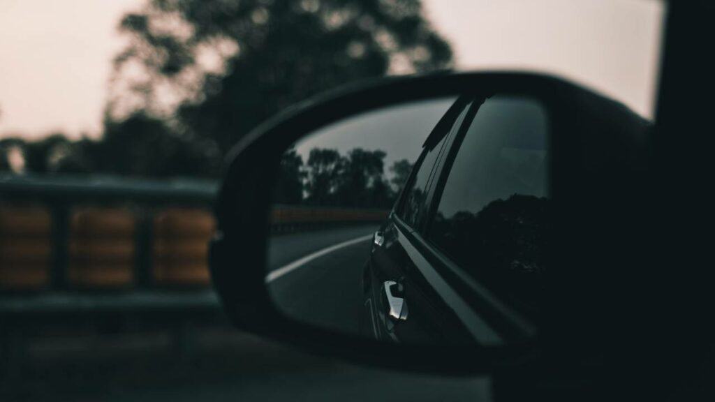 A view of a rainy day in the car's rear view mirror